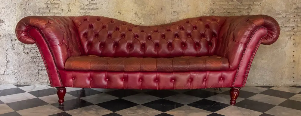A red leather couch on a tile floor